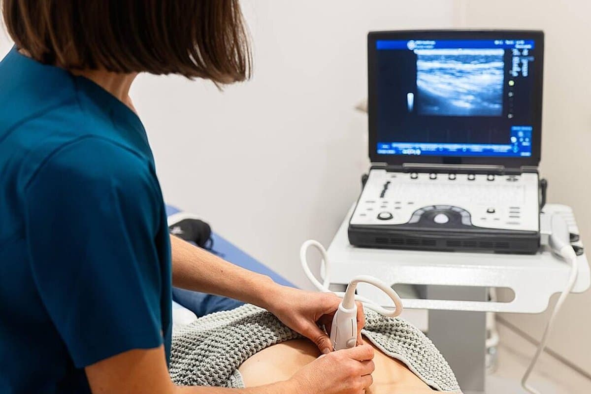 Ultrahangvizsgálat: az orvos szondával vizsgálja a pácienst, mellette az ultrahangkészülék képernyője