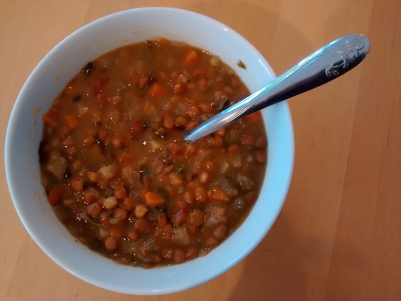 Zöldséges lencseleves sárgarépával, fehér tálban, kanállal