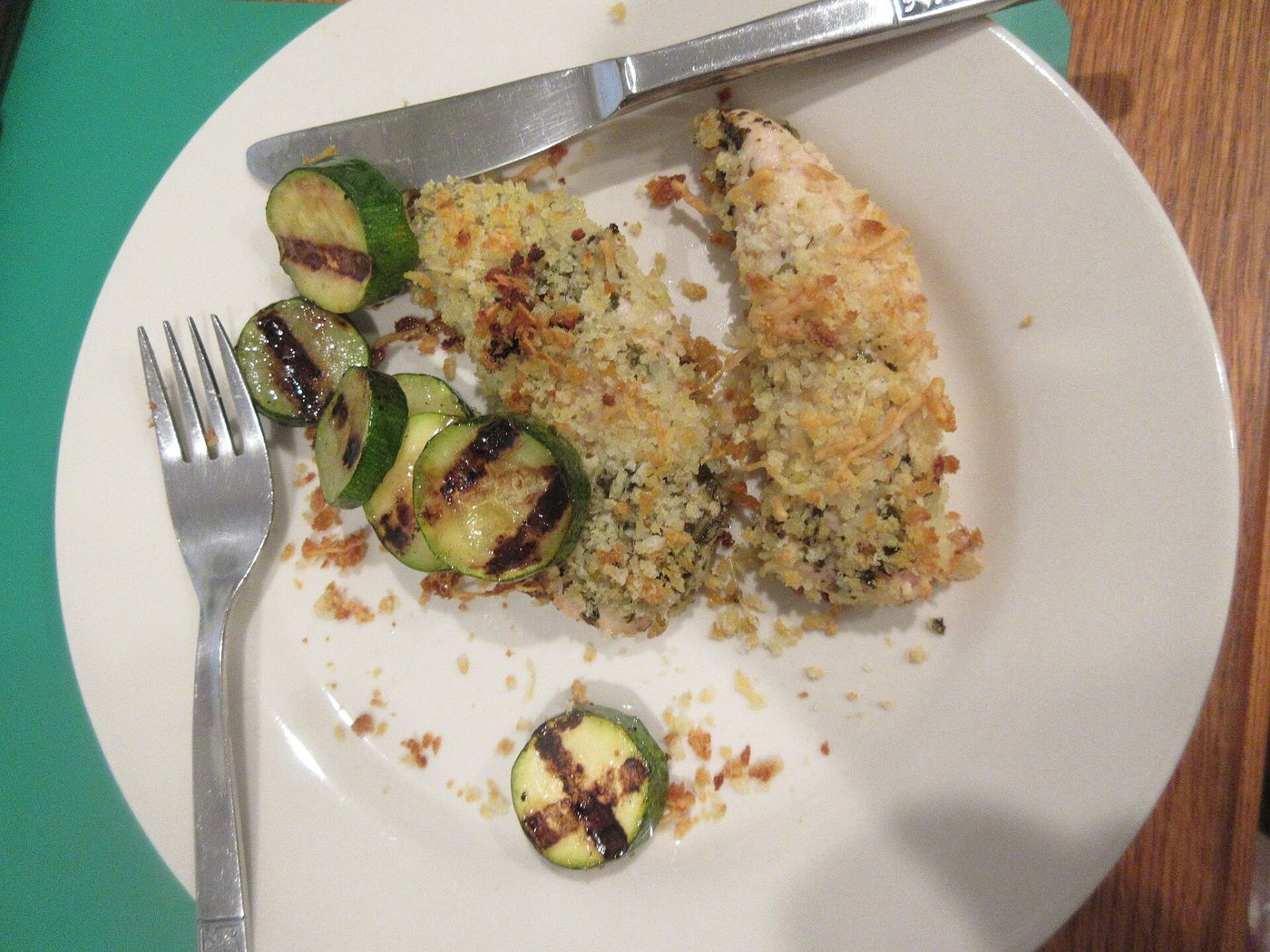 Morzsában sült, parmezános csirkemell grillezett cukkinikarikákkal, fehér tányéron