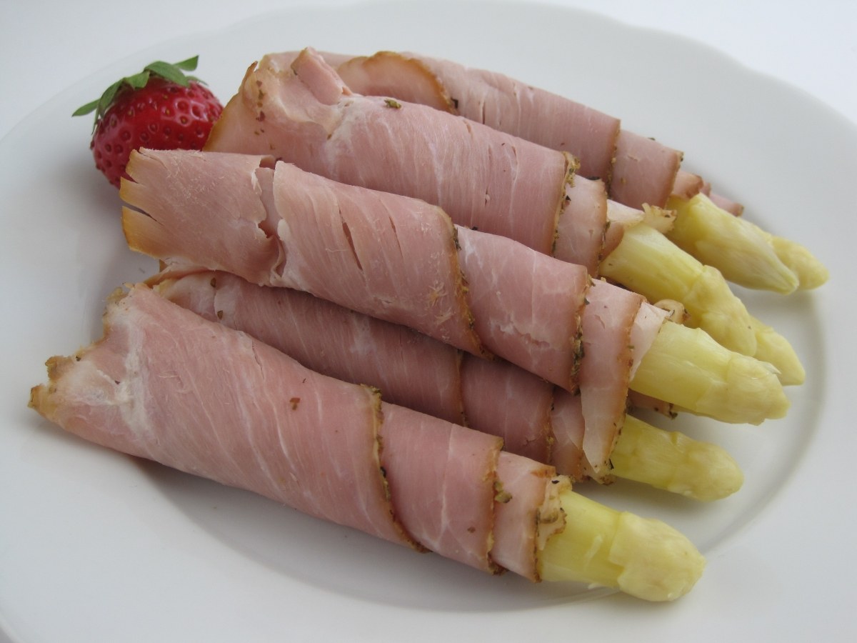 Sonkába tekert fehér spárgaszálak fehér tányéron, egy szem eperrel díszítve